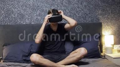 男人戴着VR耳机坐在床上。 四处看看。 观看VR视频